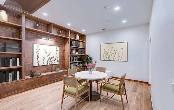 A dining room with a table set for two and a bookshelf filled with books.