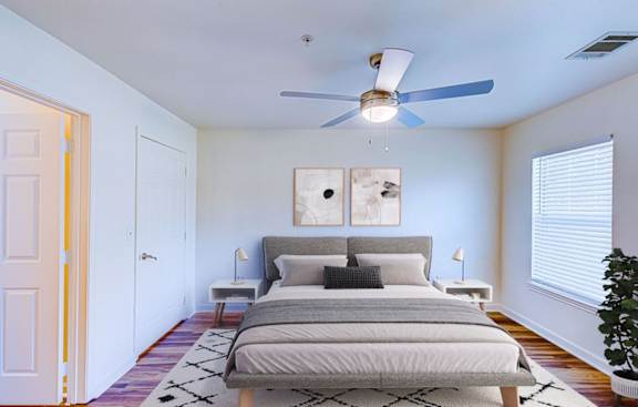 A bedroom with a bed, two lamps, and a ceiling fan.