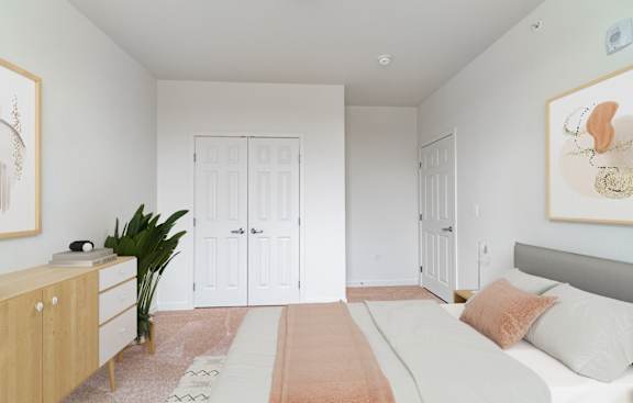 A bedroom with a bed, dresser, and a plant.