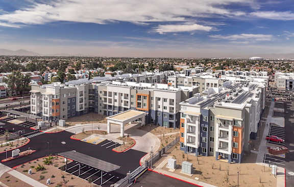 A large, modern apartment complex with a parking lot in the foreground.