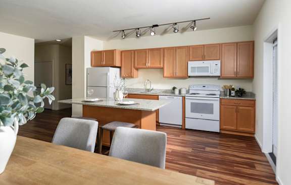 A kitchen with wooden floors and white appliances.