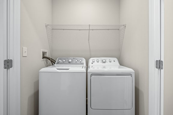 a washer and dryer in a laundry room with a white door  at Osprey Park 62&#x2B; Apartments, Kissimmee, 34758