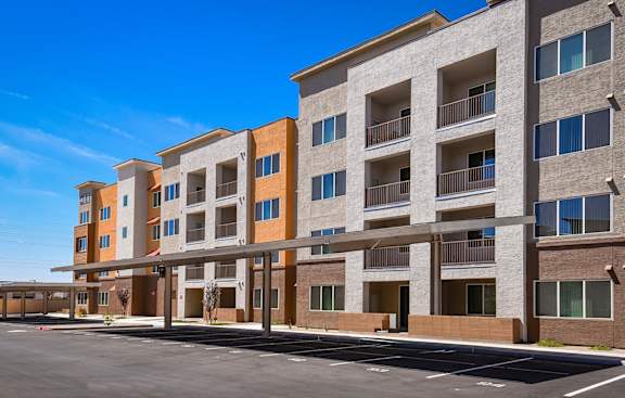 A large apartment complex with a parking lot in front.