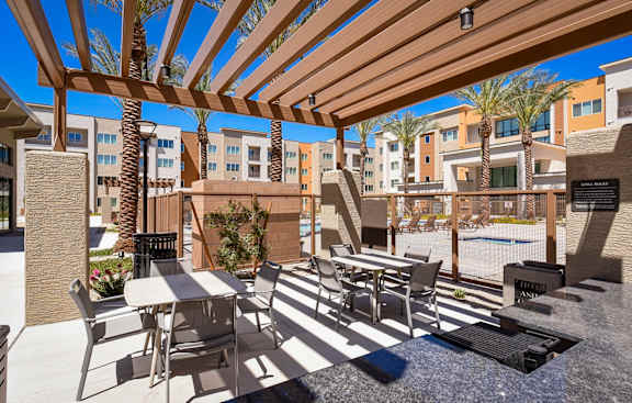 A patio with a table and chairs under a wooden pergola.