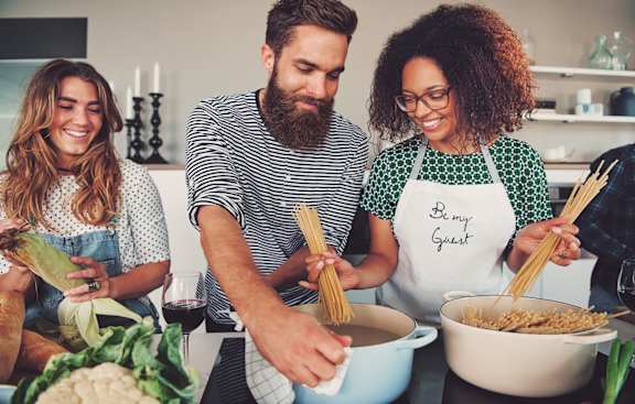 Three people are cooking together in a kitchen.