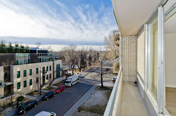 A view of a street with cars and a building with a balcony.