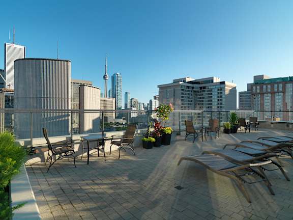 A rooftop patio with chairs and a table with a view of a city skyline.