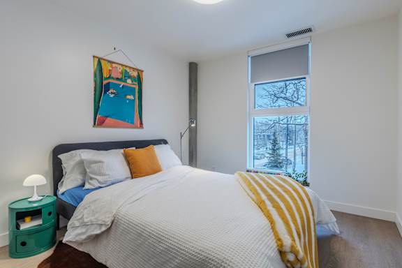 A bedroom with a bed, a nightstand, and a window.