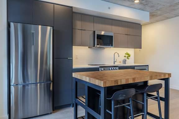 A modern kitchen with a wooden island and stainless steel appliances.