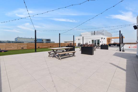 A patio with a table and chairs is surrounded by a fence and has a building in the background.
