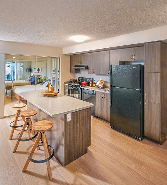 A kitchen with a black refrigerator and wooden floors.