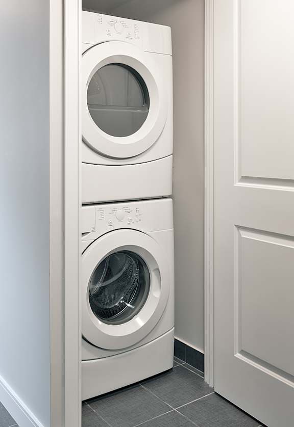 A white front loading washing machine in a laundry room.