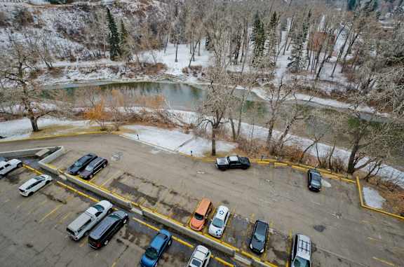 A parking lot with cars and a river in the background.