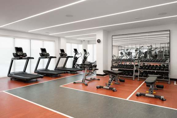 A gym with treadmills, weights, and exercise equipment.