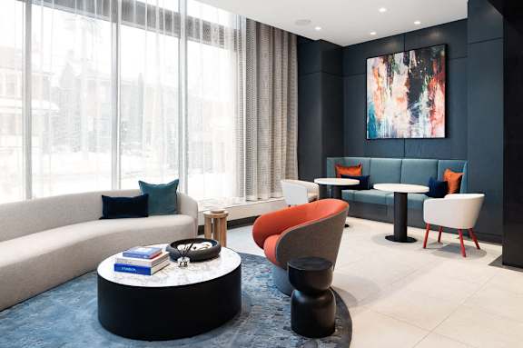 A modern living room with a large window and a painting on the wall.