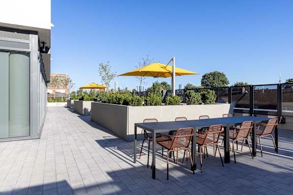 A patio with a table and chairs and umbrellas.