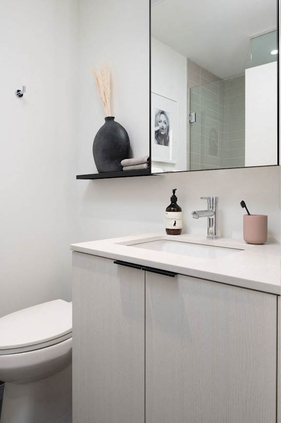 A bathroom with a toilet, sink, and a mirror.
