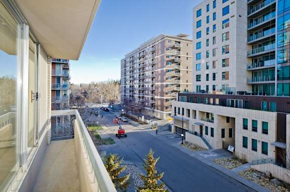 A view from a balcony overlooking a street with cars and buildings.