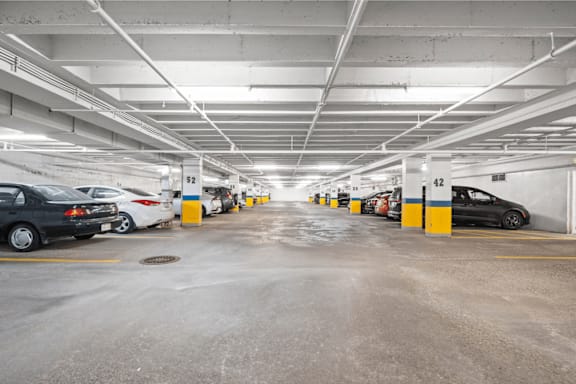 A parking garage with cars parked in yellow and blue marked spots.