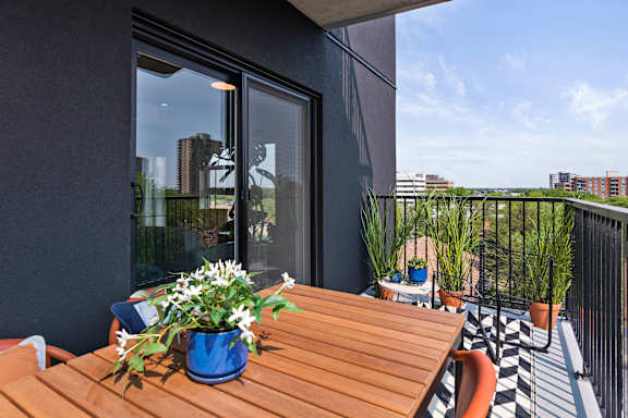 A balcony with a table and chairs and a view of the city.