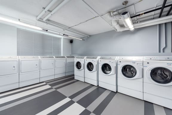 A row of white front load washing machines in a laundromat at Clayton on the Park Apartments, Clayton