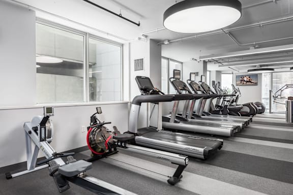 A gym with treadmills, elliptical machines, and a rowing machine at Clayton on the Park Apartments, Missouri