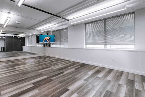 A spacious room with wooden flooring and a large screen displaying an orange figure at Clayton on the Park Apartments, Missouri, 63105
