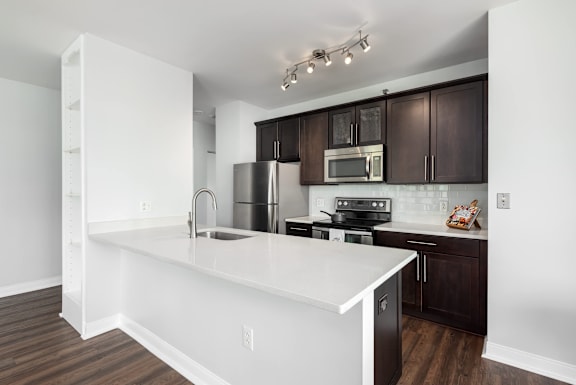 A kitchen with white countertops and dark brown cabinets at Clayton on the Park Apartments, Missouri, 63105