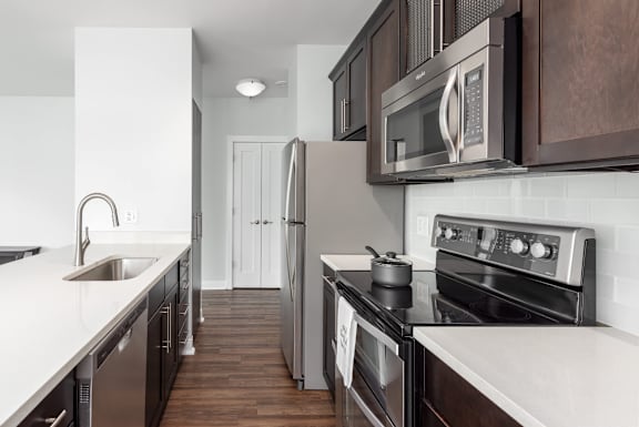 A modern kitchen with dark wood cabinets and stainless steel appliances at Clayton on the Park Apartments, Clayton, Missouri