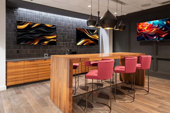 A modern kitchen with a wooden island and red chairs at Clayton on the Park Apartments, Clayton 63105