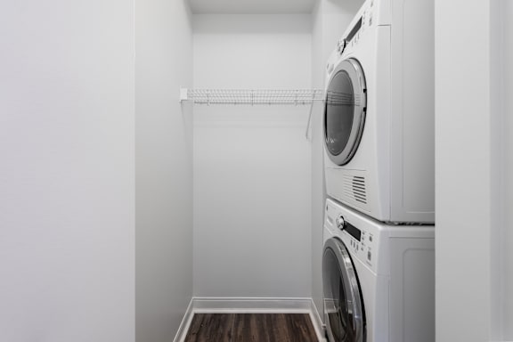 A white laundry room with a washer and dryer stacked on top of each other at Clayton on the Park Apartments, Clayton, MO, 63105