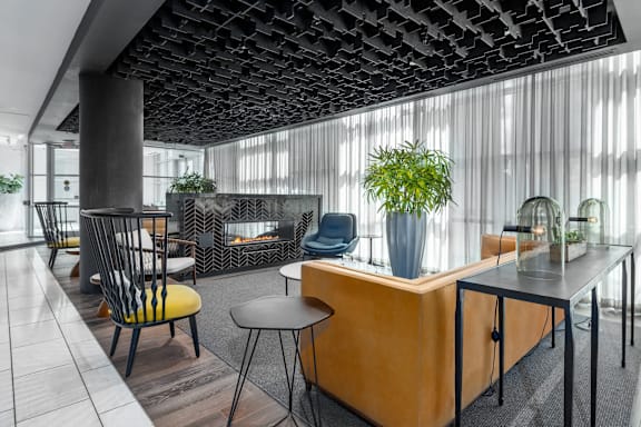 A modern office space with a wooden reception desk and black chairs at Clayton on the Park Apartments, Clayton 63105
