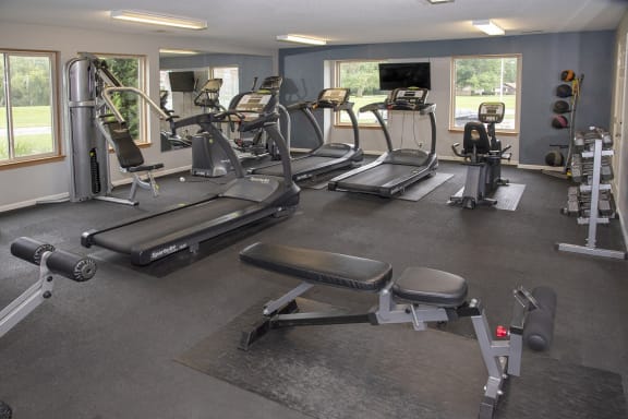 a gym with cardio equipment and weights on the floor