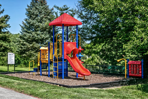a playground with a red slide and a blue and yellow swing set