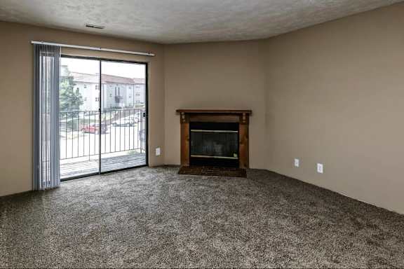 an empty living room with a fireplace and a sliding glass door