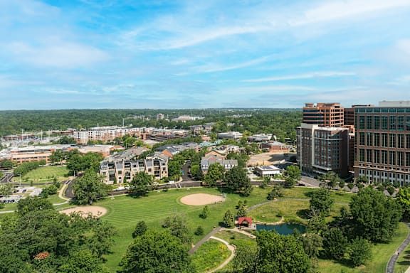 A view of a city from a high vantage point with buildings, trees, and a baseball field at Clayton on the Park Apartments, Clayton 63105