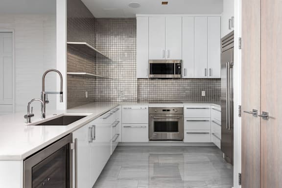 A modern kitchen with white cabinets and a tiled backsplash at Clayton on the Park Apartments, Missouri