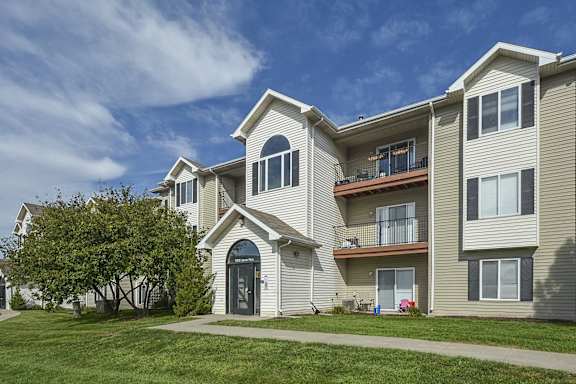 the exterior of a apartment building with a sidewalk and grass