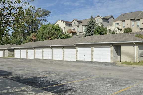 a row of white garages in a parking lot with houses in the background