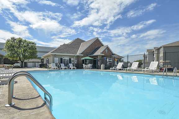 a swimming pool with chairs and a building in the background