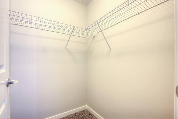 a walk in closet with empty shelves in a white room