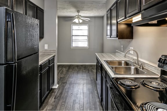 an empty kitchen with stainless steel appliances and black cabinets
