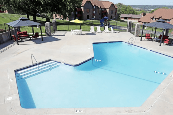 an empty swimming pool with umbrellas and chairs around it at a resort