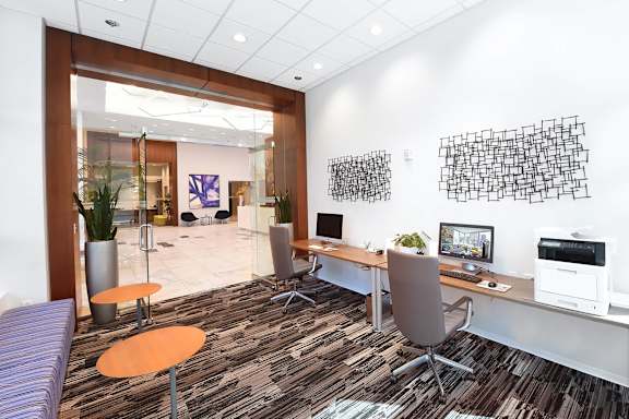A modern office with a purple sofa and a wooden desk at Two Twelve Clayton Apartments, Clayton, Missouri