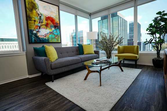 A living room with a grey couch and yellow pillows at Two Twelve Clayton Apartments, Clayton, Missouri
