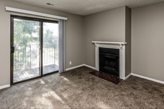 an empty living room with a fireplace and a patio door