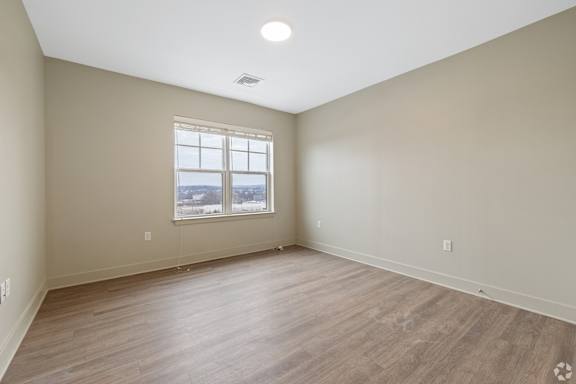 Empty room with a window and wooden flooring.
