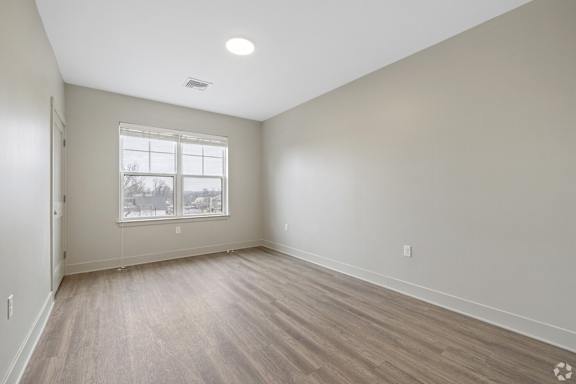A room with a window and wooden flooring.