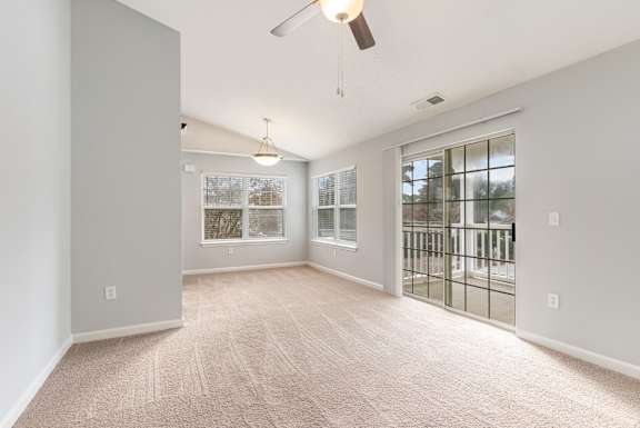 A room with a fan and a window with a view of a tree.