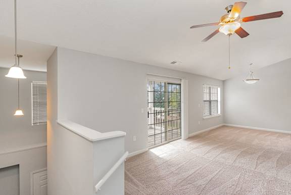 A room with a ceiling fan and a window with blinds.